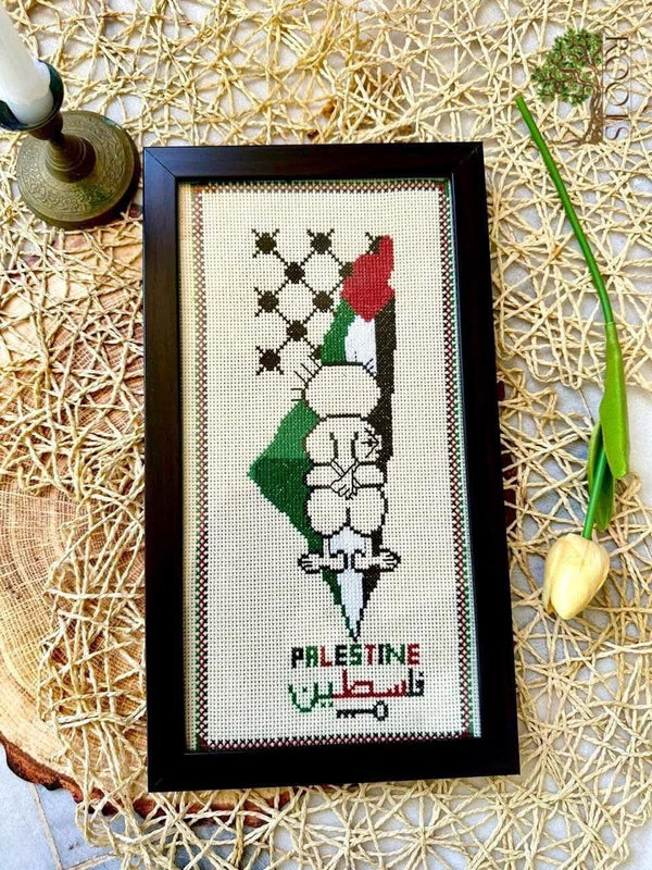 Handala within a Palestine map with flag colours and keffiyeh pattern, photographed in a frame