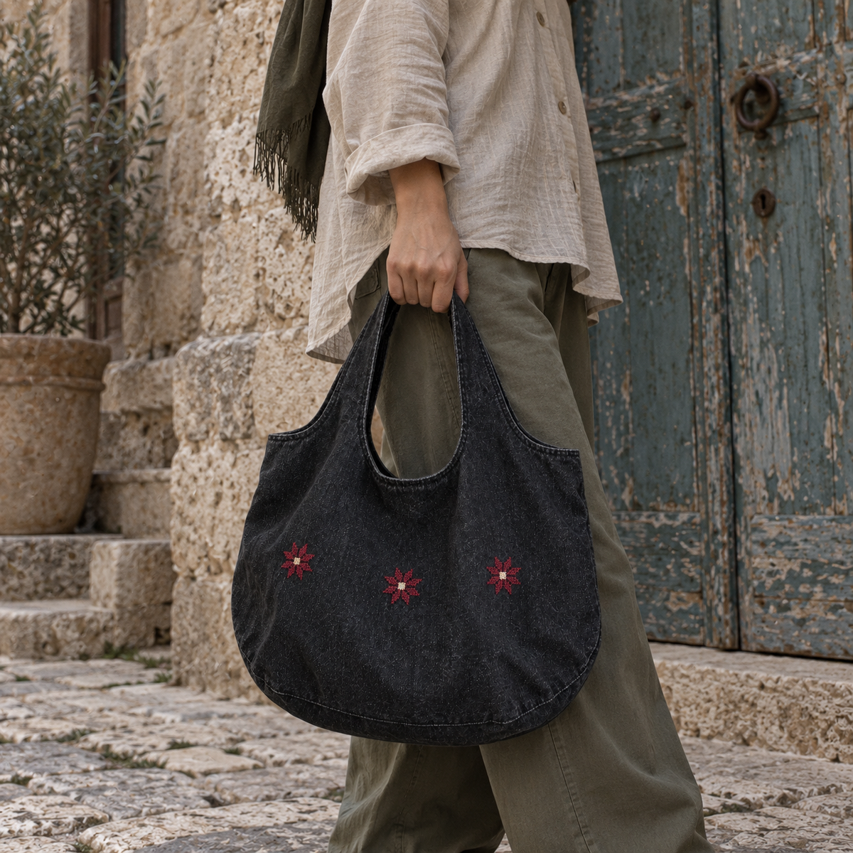 Rounded charcoal denim tote with three burgundy Bethlehem stars carried by its broad handles