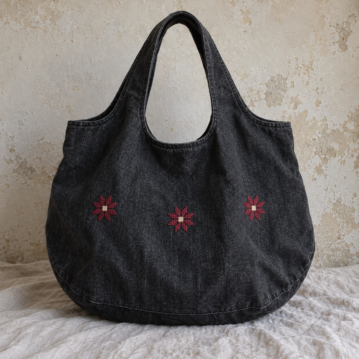 Rounded charcoal denim tote with three burgundy Bethlehem star motifs