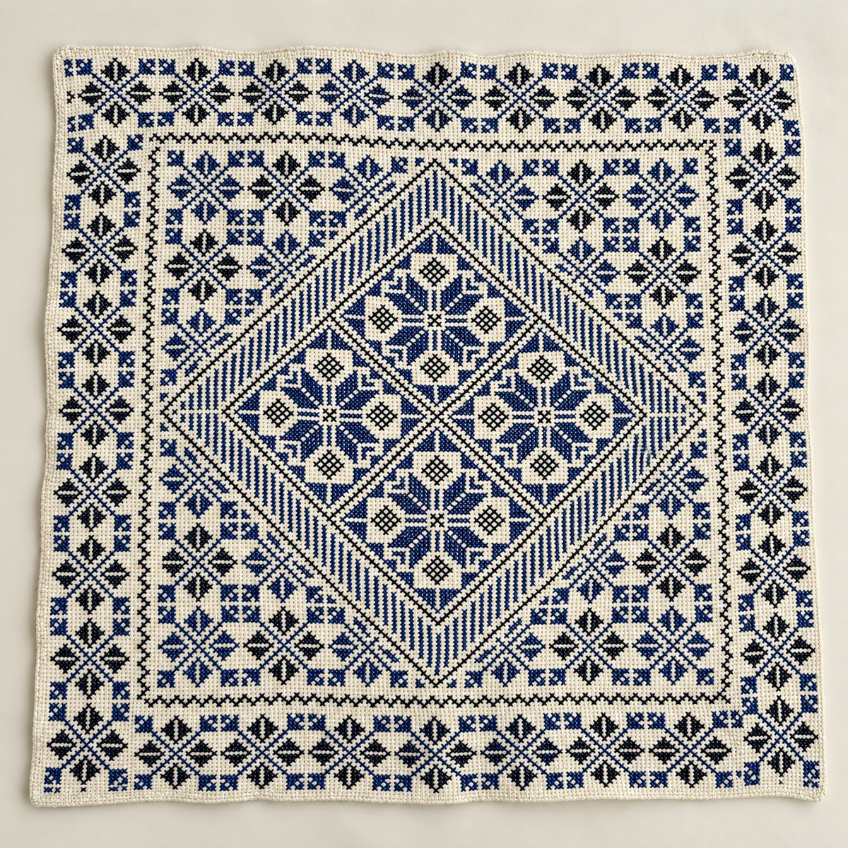 Blue floral diamond tatreez cushion cover laid flat showing the embroidered front