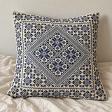 Blue floral diamond cushion cover styled on an insert against a neutral wall