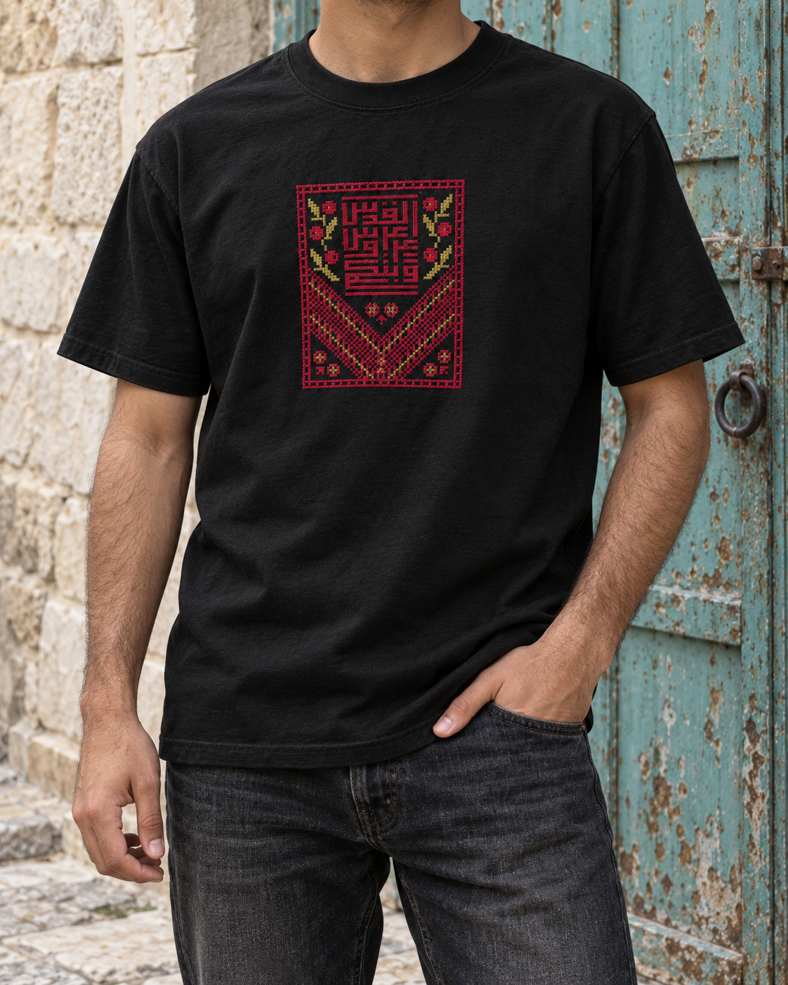Black Kufic Floral Tatreez T-Shirt worn with dark jeans beside a turquoise door
