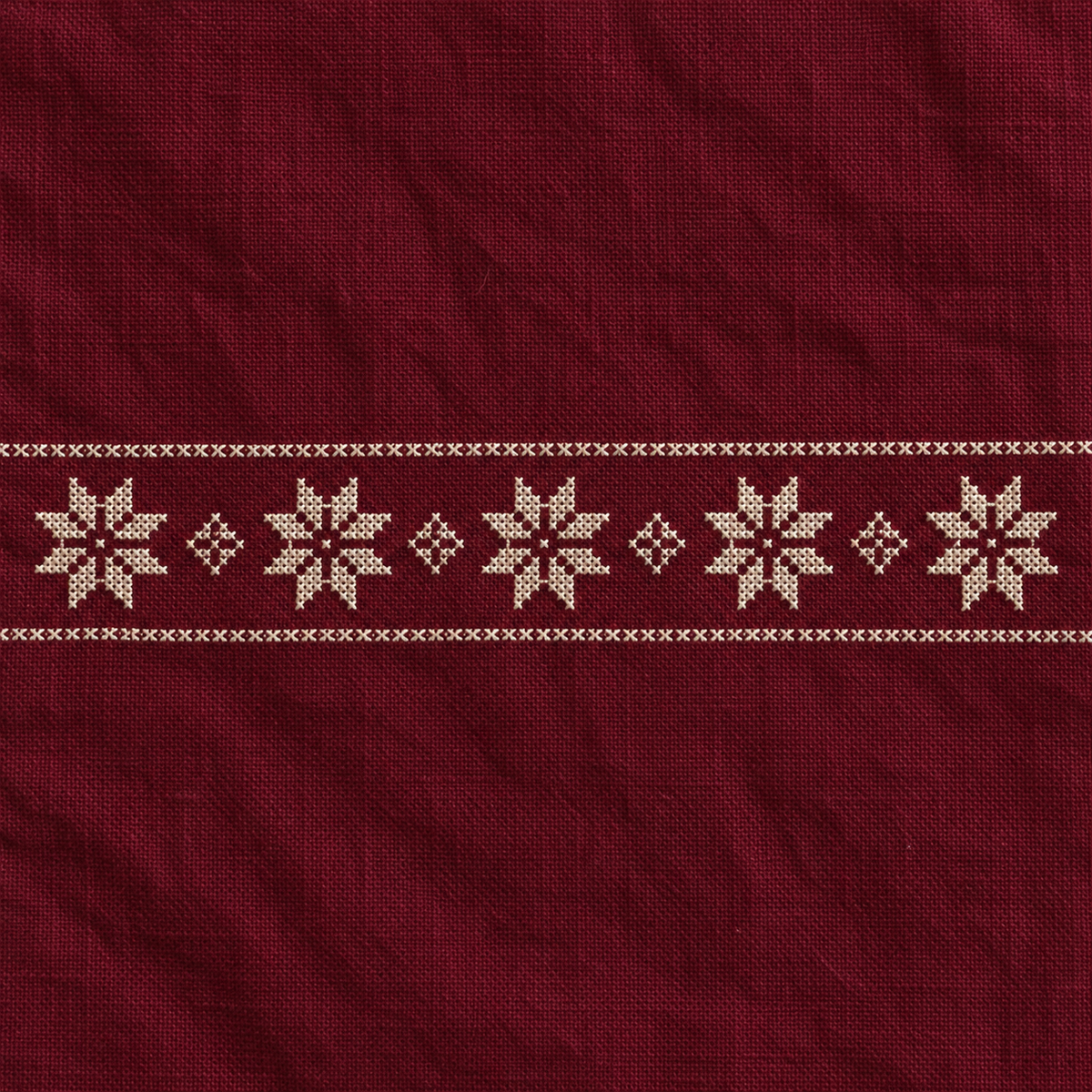 Close-up of five ivory tatreez stars and diamond motifs stitched on burgundy cotton