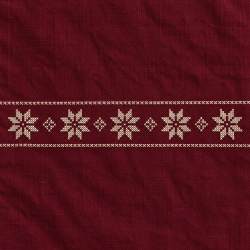 Close-up of five ivory tatreez stars and diamond motifs stitched on burgundy cotton