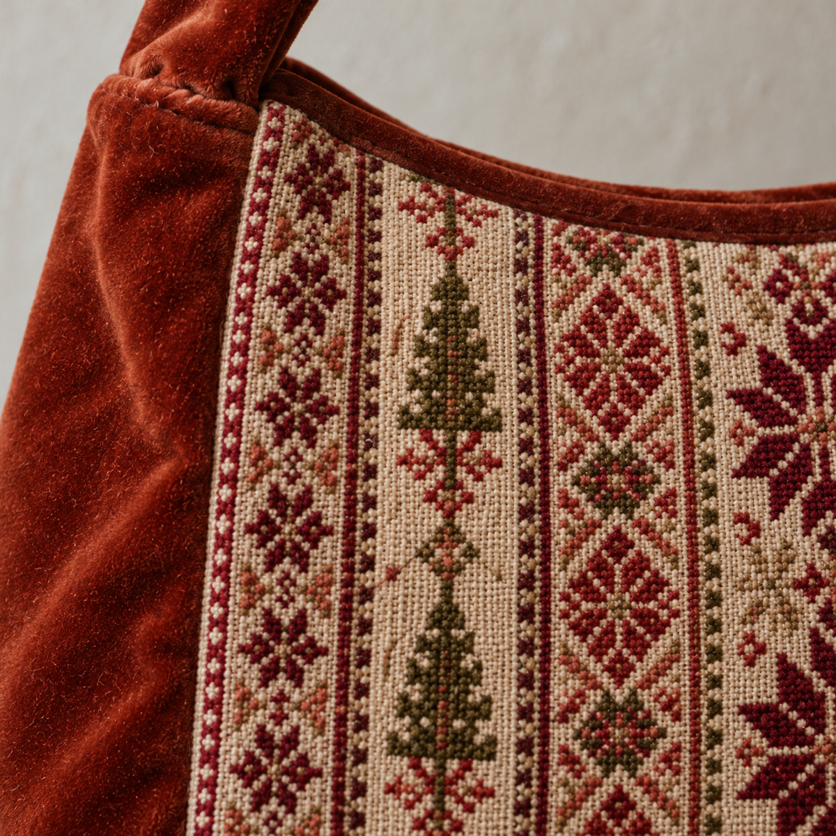 Close-up of burgundy and olive tatreez stitches and cinnamon velvet
