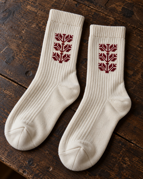 Design mock-up of coffee bean tatreez socks in cream, showing cross-stitch details.