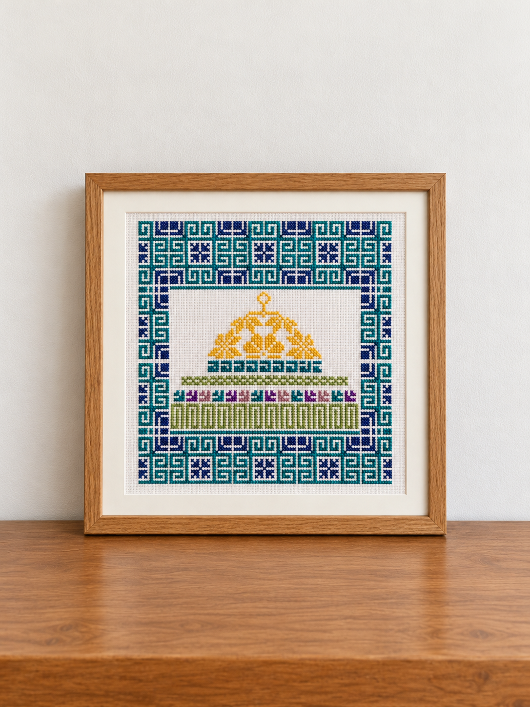 Framed Dome of the Rock tatreez art with a gold dome and teal and navy geometric border