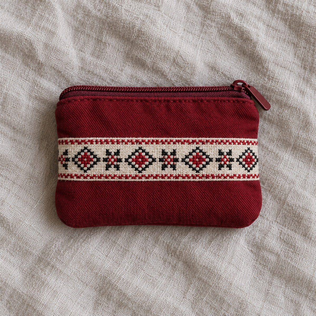 Burgundy cotton coin purse with red and dark geometric tatreez on an ivory band