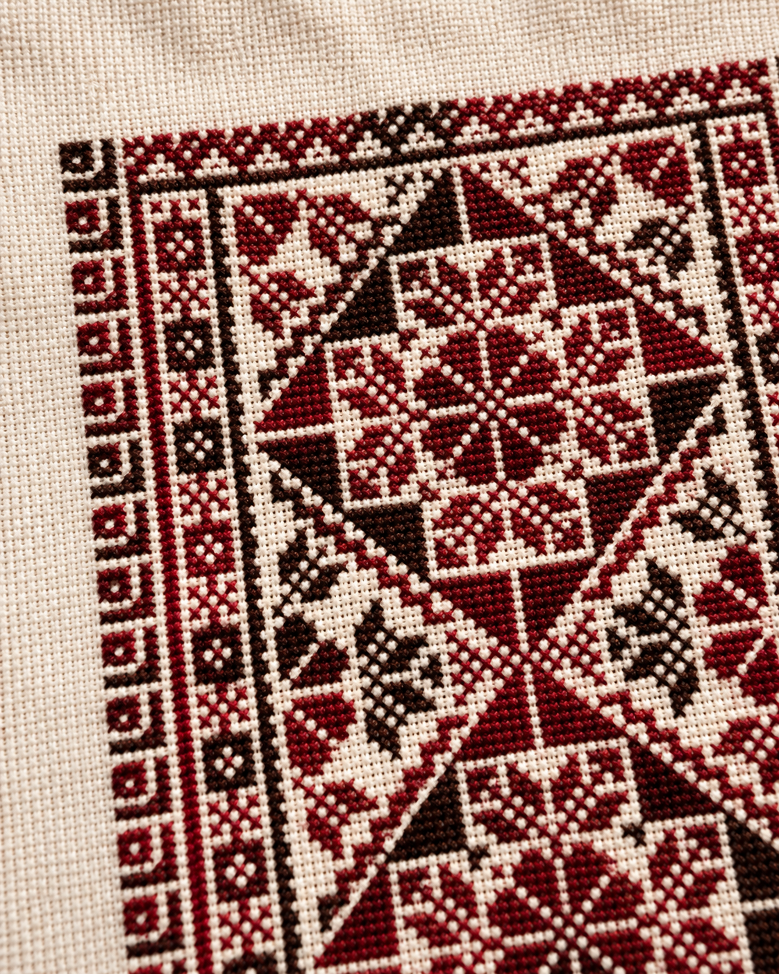Intricate burgundy and dark tatreez art on ivory fabric - detail