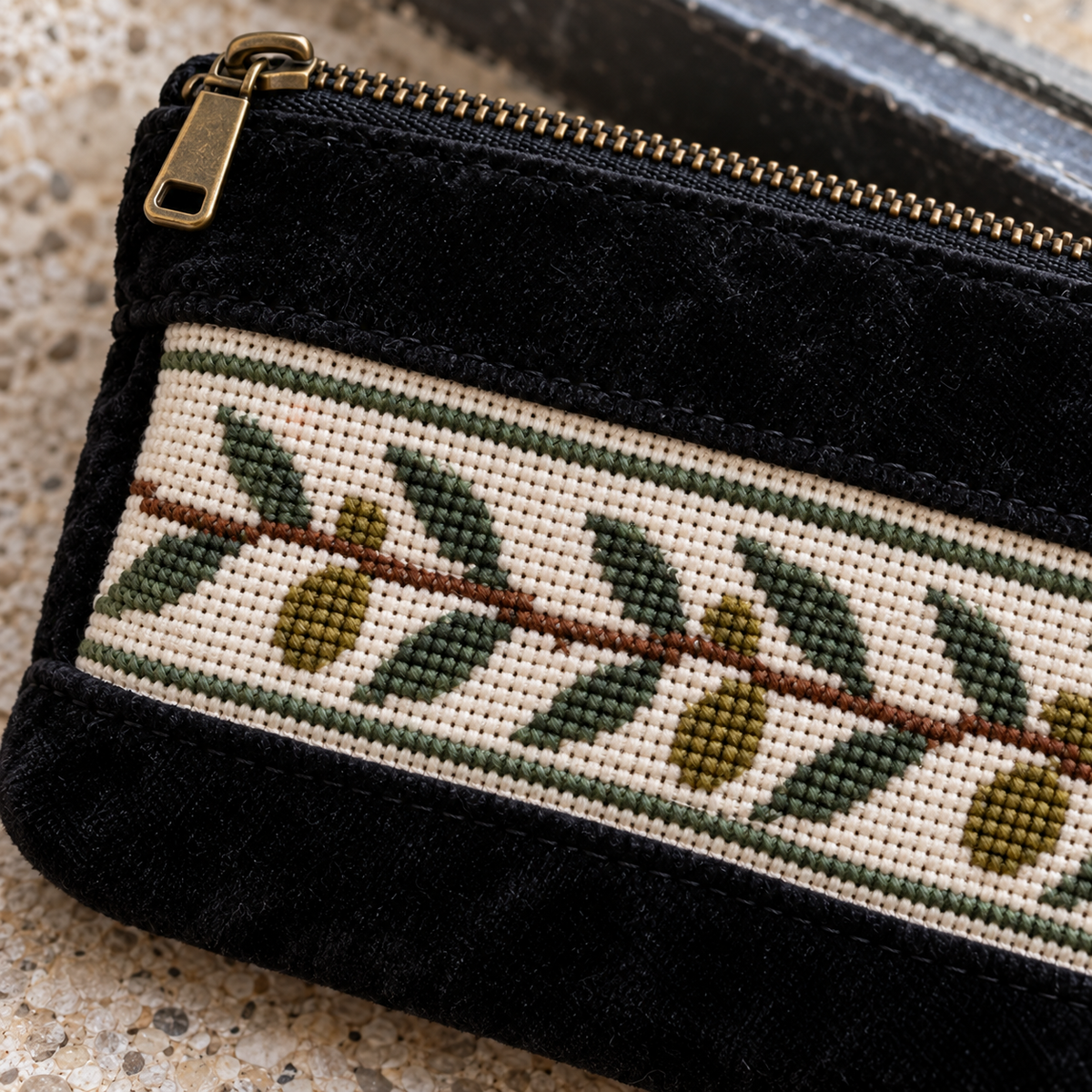 Close-up of olive branch cross stitches and standard brass-coloured zip on the coin purse
