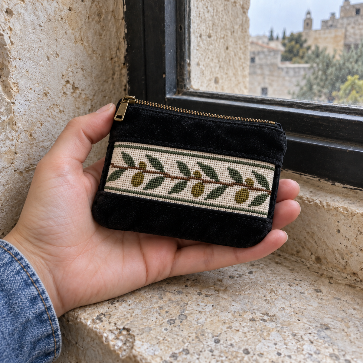 Olive tatreez coin purse held in a hand to show its compact size