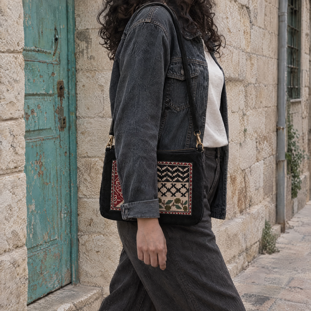 Palestine flag tatreez shoulder bag worn at the hip with a dark denim jacket