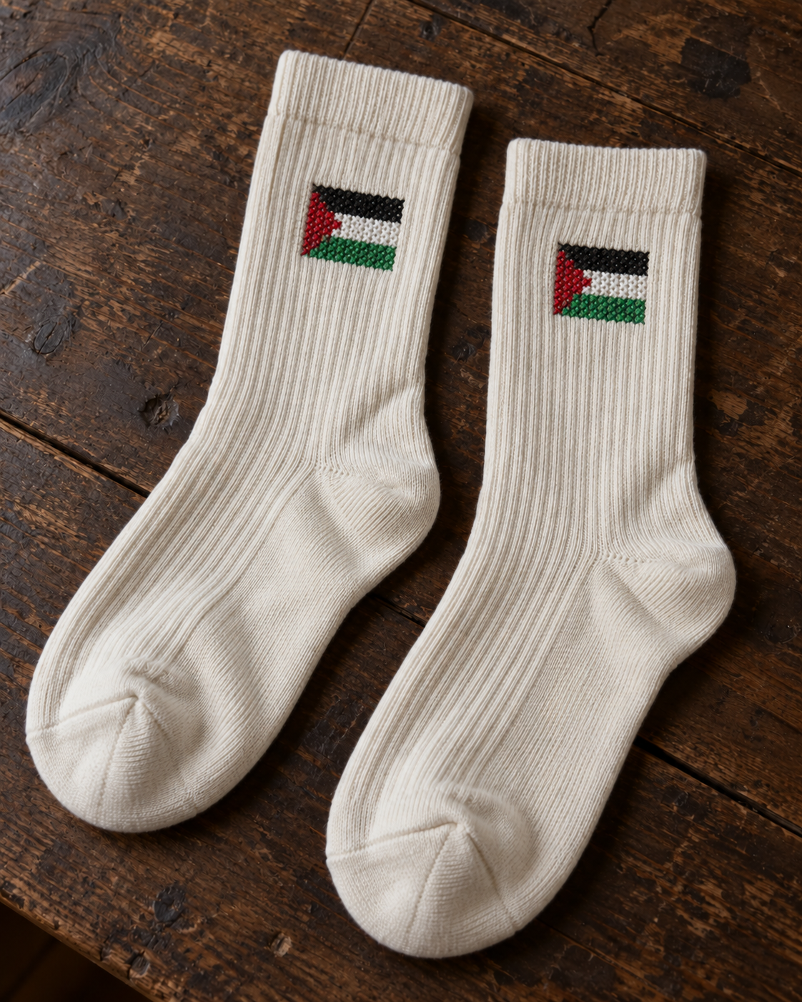 Design mock-up of palestine flag tatreez socks in cream, showing cross-stitch details.