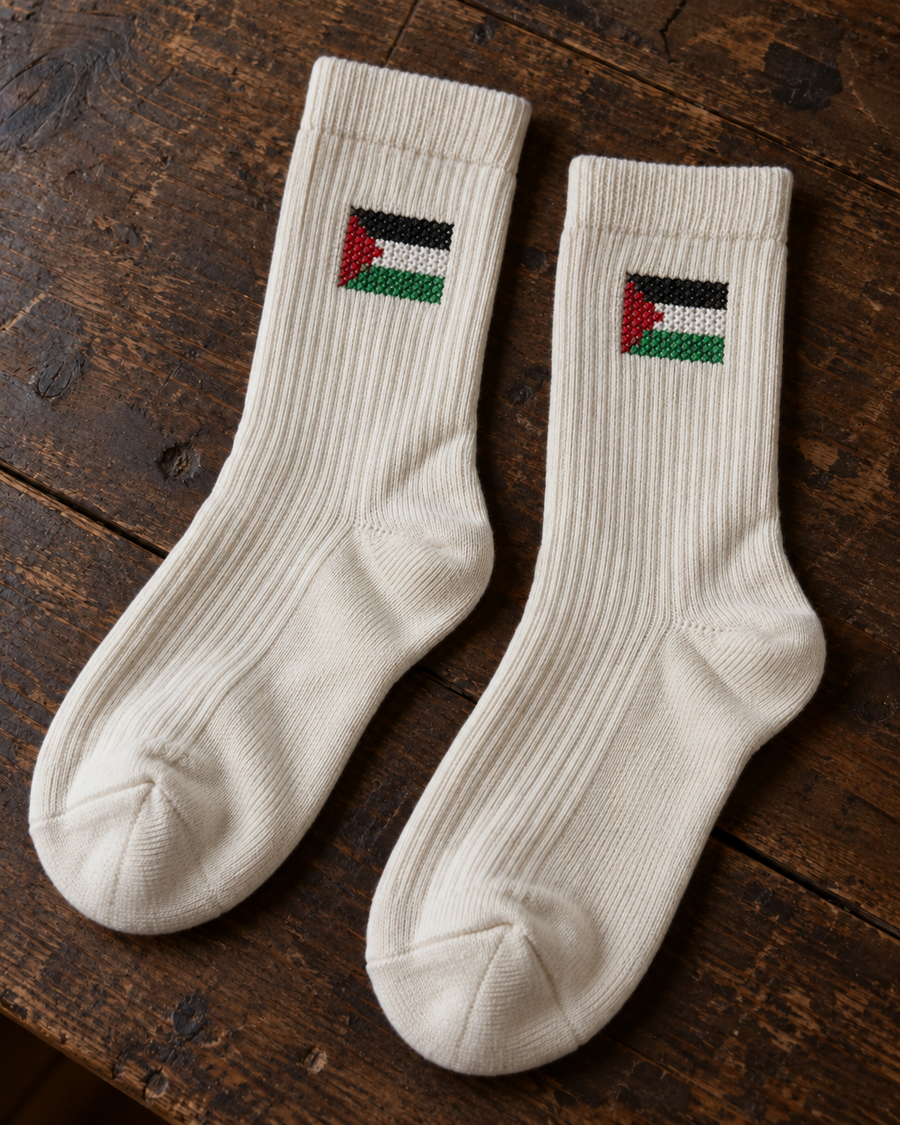 Design mock-up of palestine flag tatreez socks in cream, showing cross-stitch details.