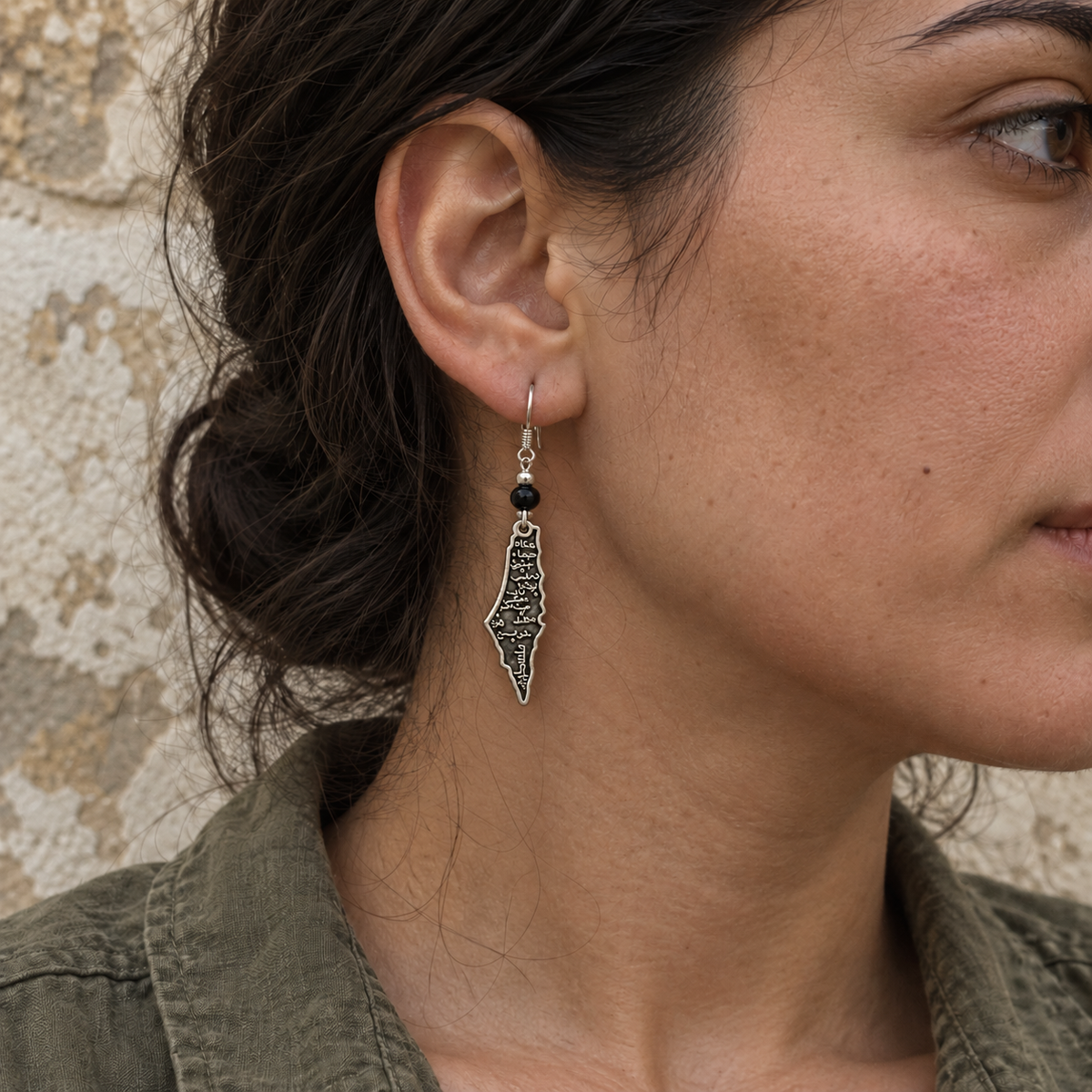 Small Palestine map earring with round black bead worn on a model
