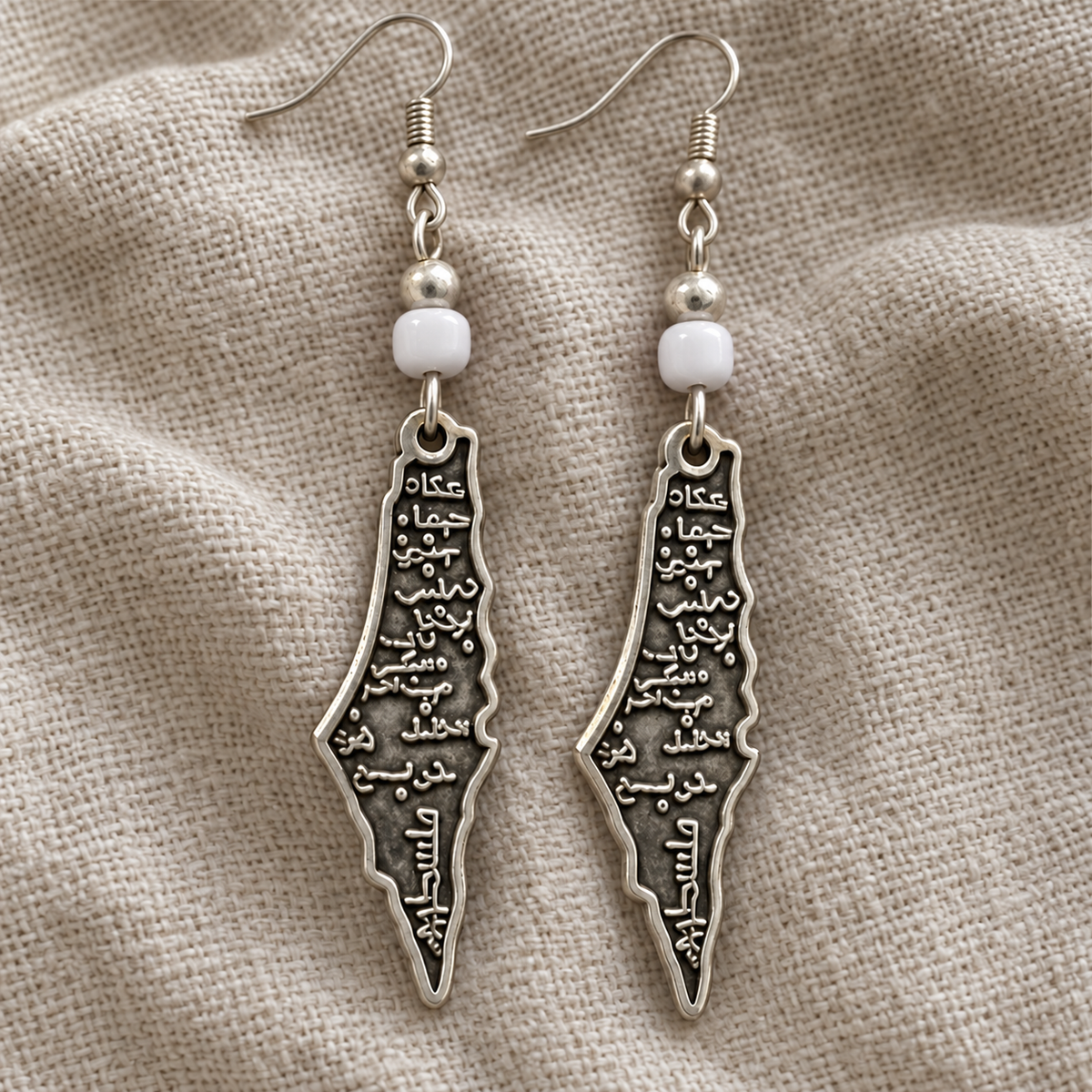 Palestine map earrings with white barrel beads and revised Arabic lettering