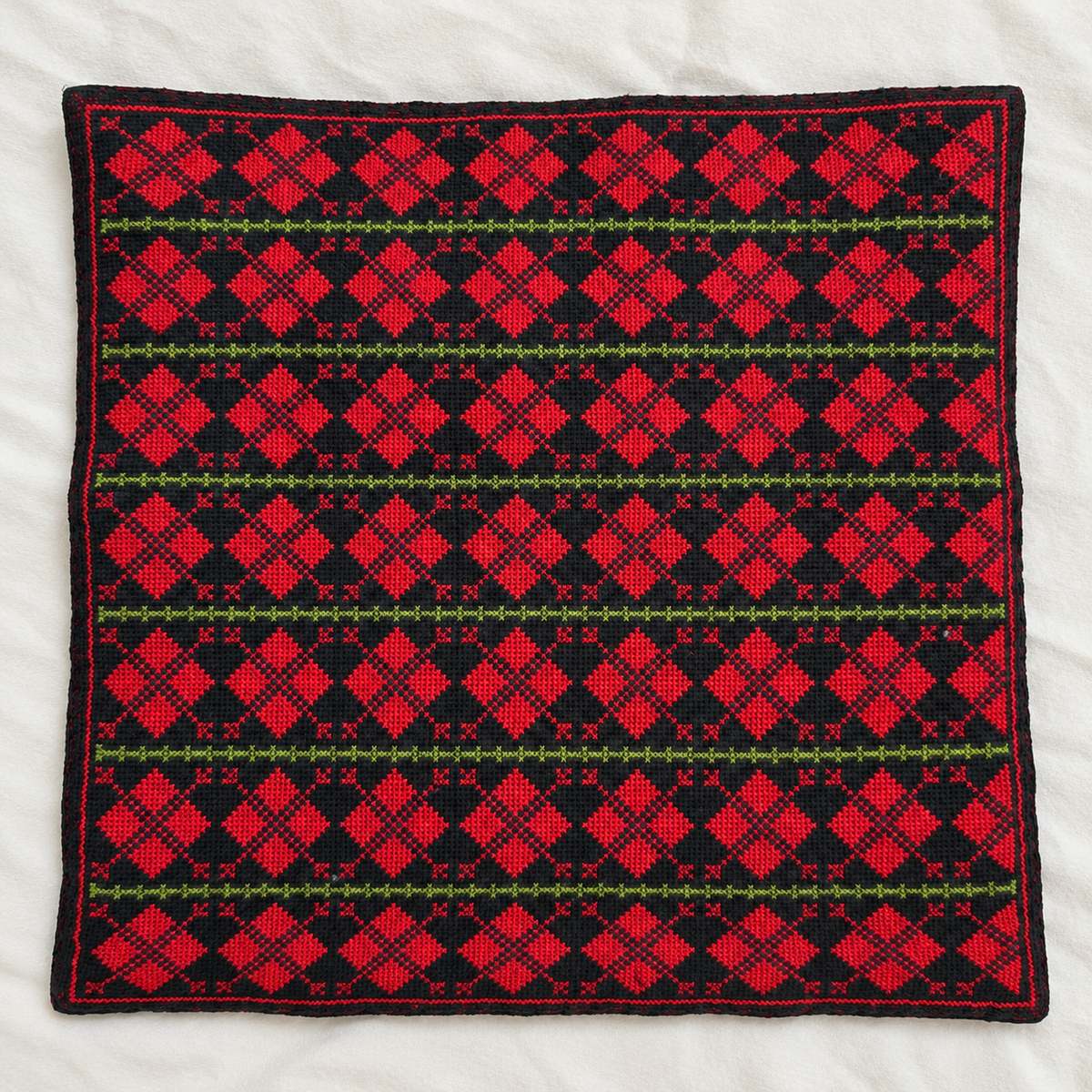 Red diamond rows tatreez cushion cover on black, flat view with seven embroidered rows
