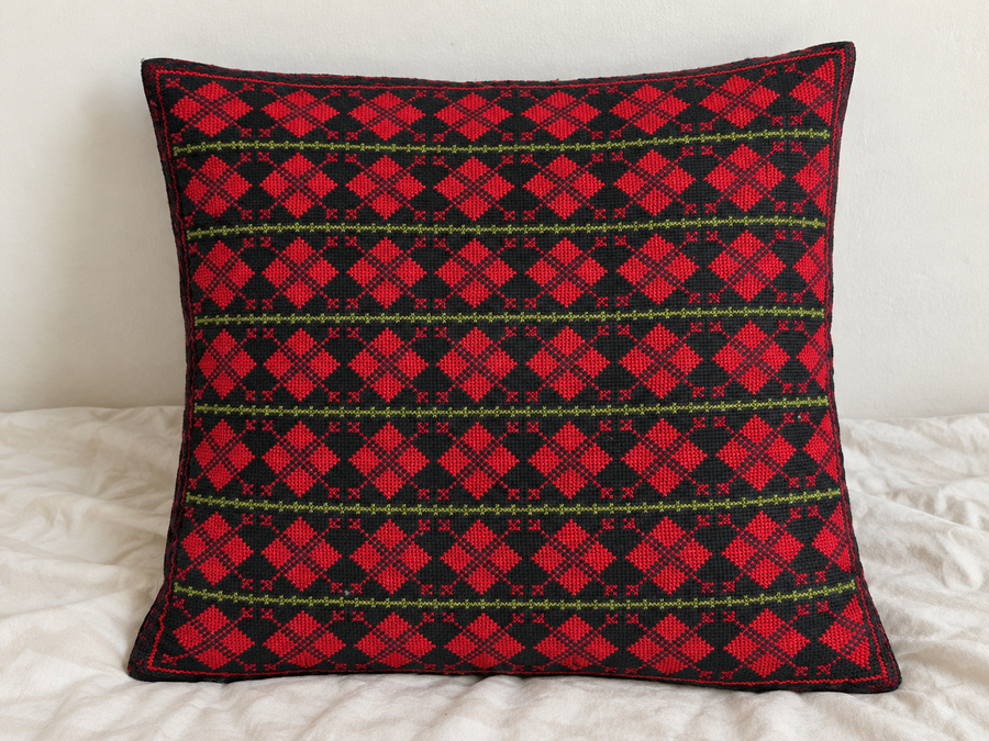 Red diamond rows tatreez cushion cover styled on an insert, seven embroidered rows