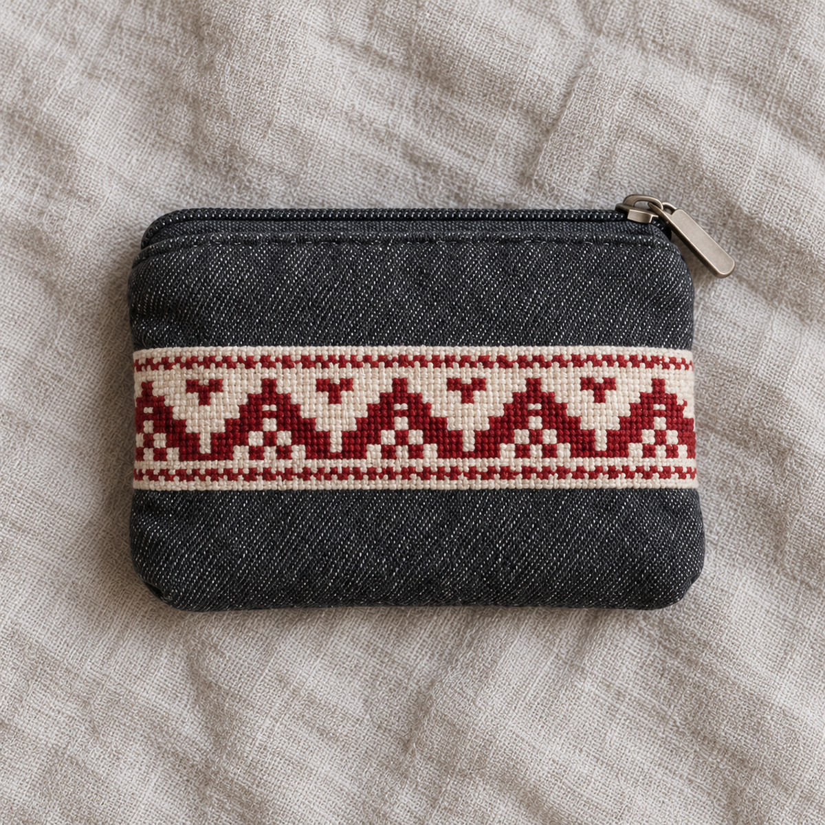Charcoal denim coin purse with a red geometric tatreez band and a dark zip