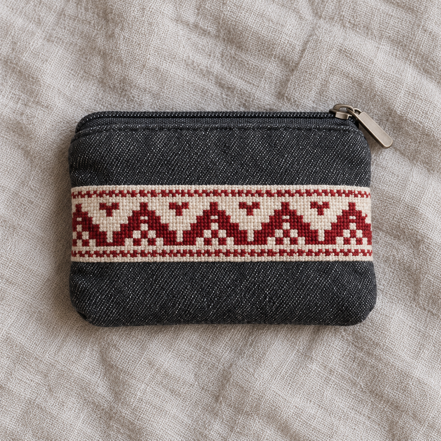 Charcoal denim coin purse with a red geometric tatreez band and a dark zip