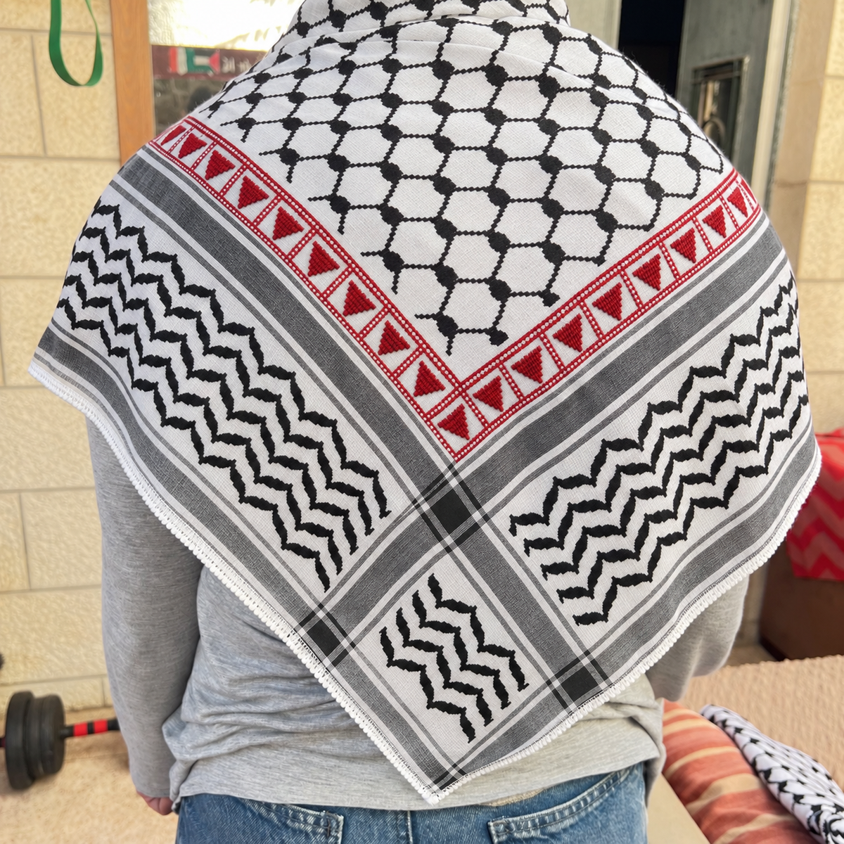 Red triangle tatreez keffiyeh worn over the shoulders, back view