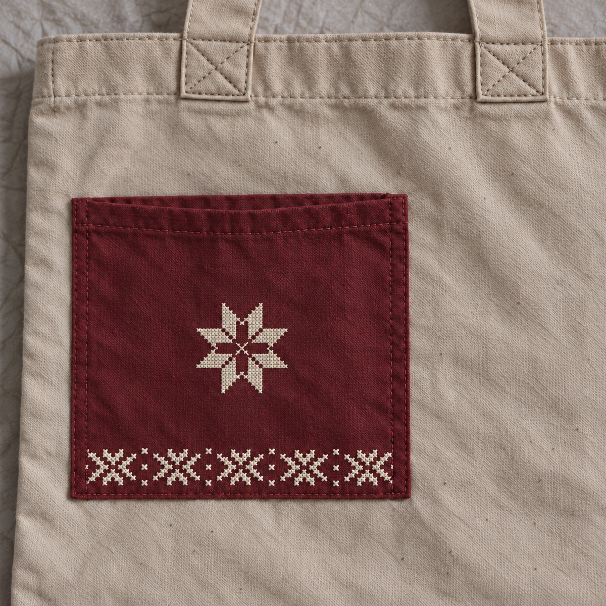 Close-up of centred ivory tatreez star and border on muted burgundy pocket