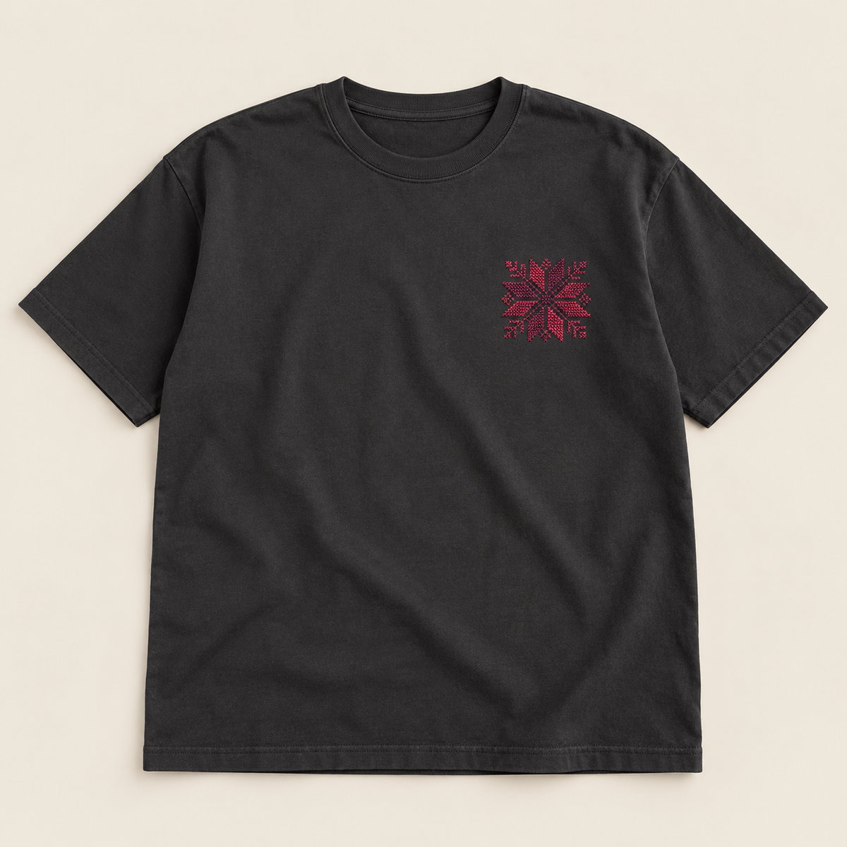Charcoal T-shirt laid flat with a small burgundy floral star embroidered on the left chest.