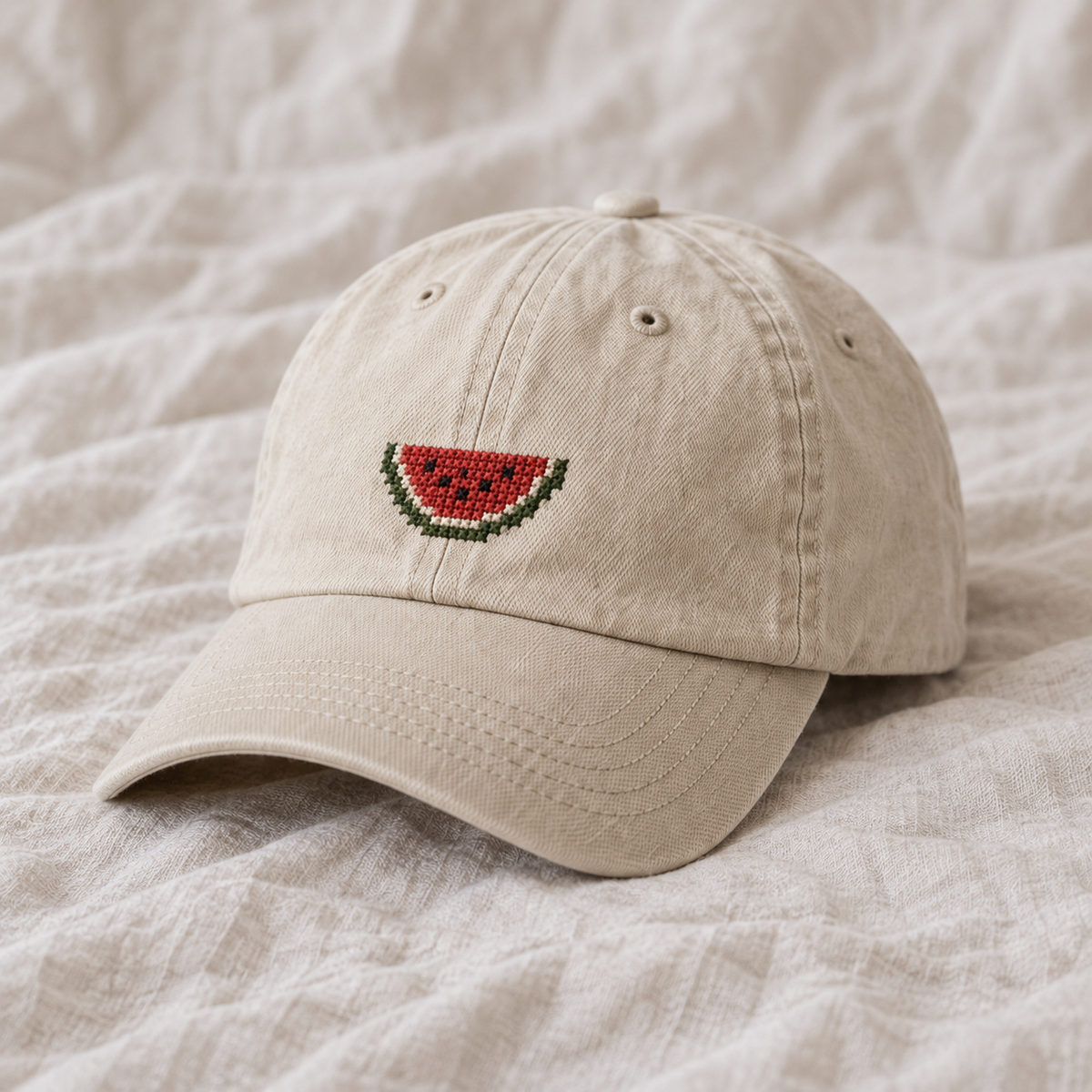 Cream washed cotton cap, single small red watermelon wedge with green rind and black seeds.