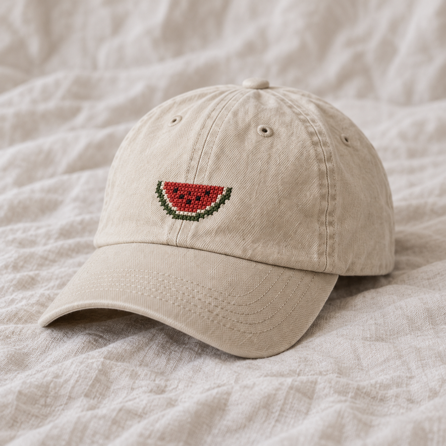 Cream washed cotton cap, single small red watermelon wedge with green rind and black seeds.