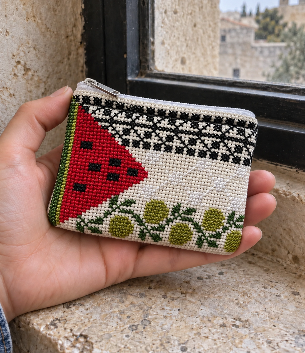 Small watermelon and olive tatreez coin purse held in one hand